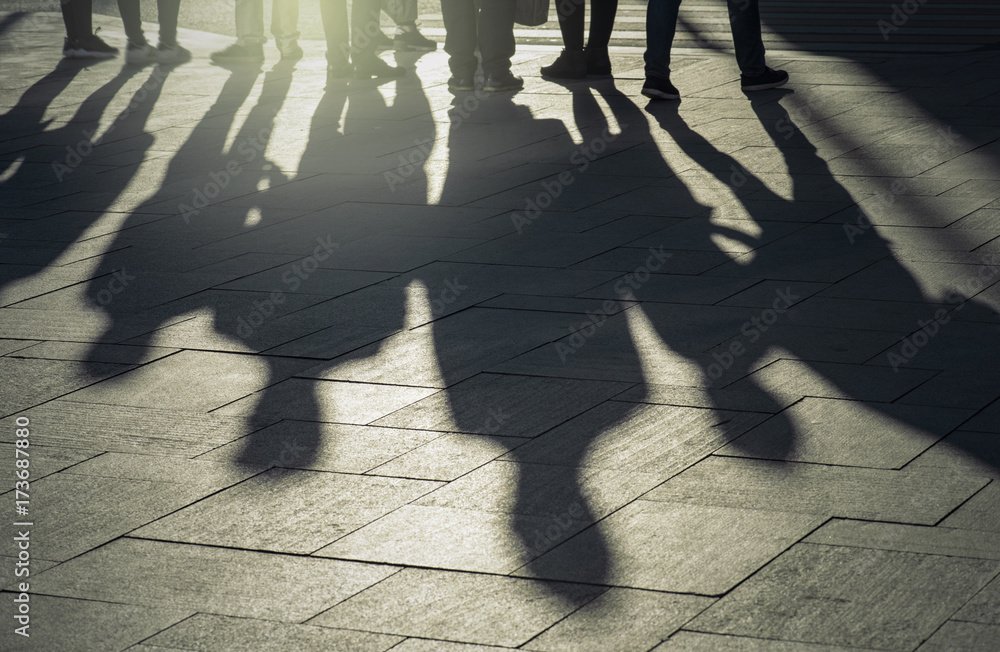 Shadows and silhouettes of people at a city during sunset